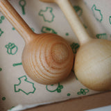 Two wooden baby rattles on a patterned surface