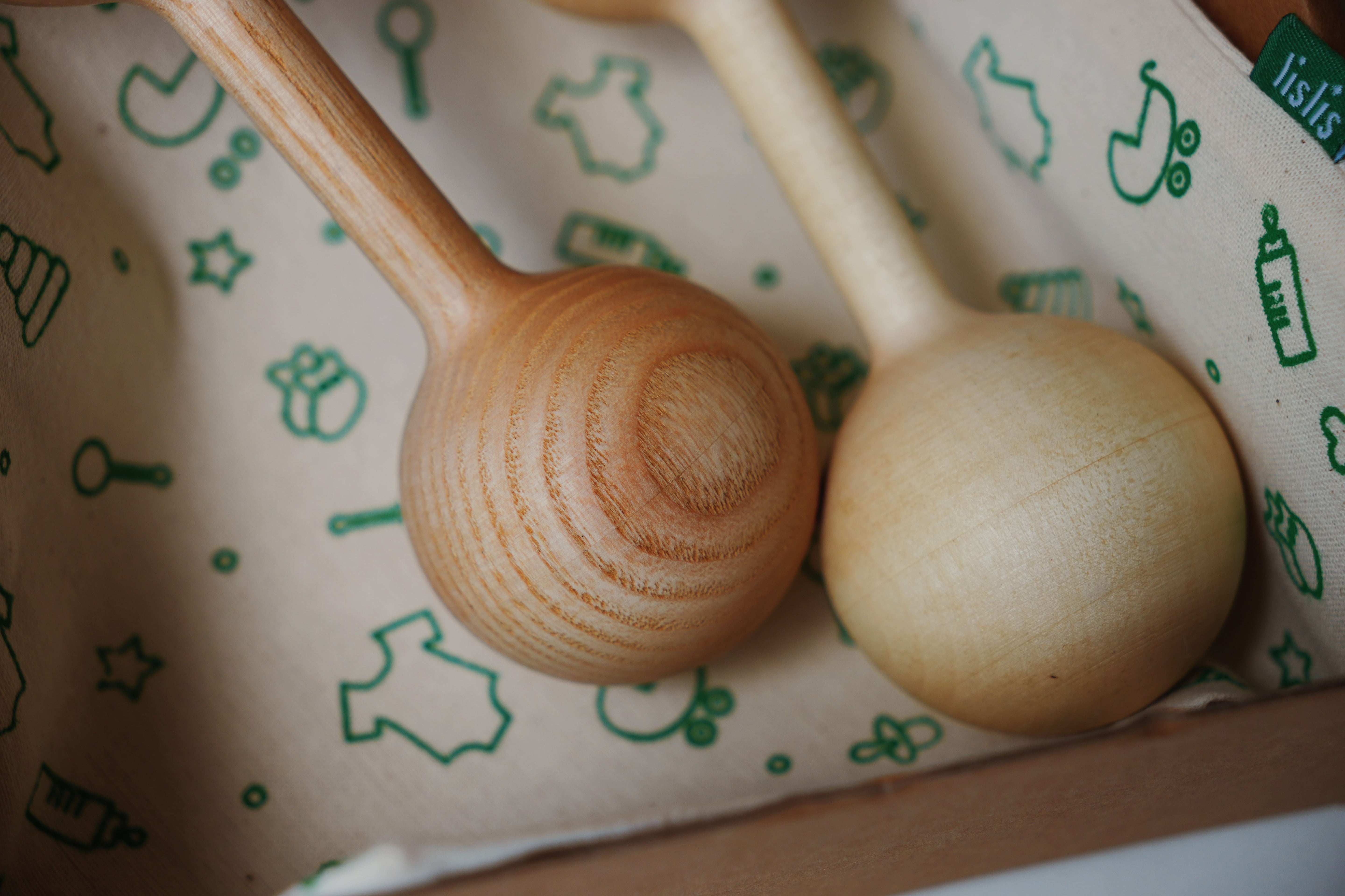 Two wooden baby rattles on a patterned surface