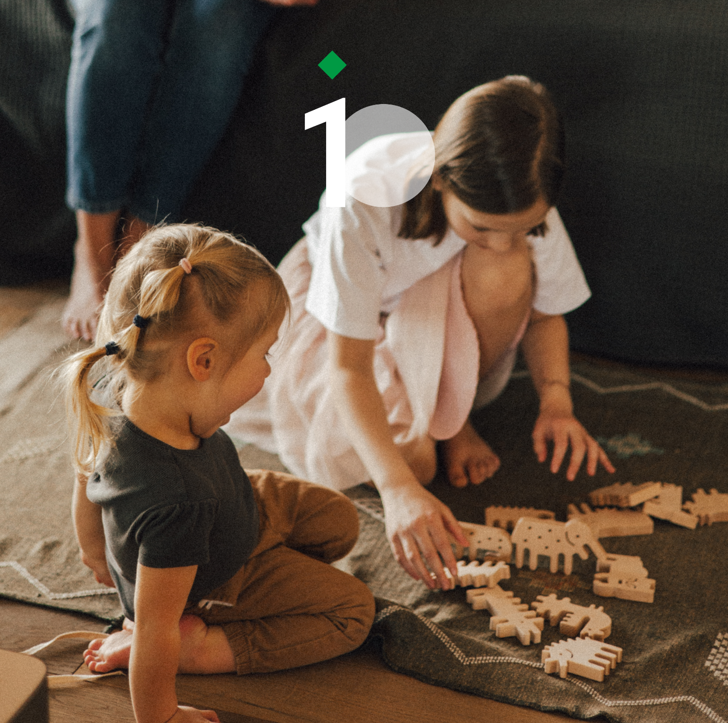 Two children playing with wooden animal blocks on a blanket.