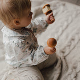 Baby sitting on a textured blanket holding wooden toys
