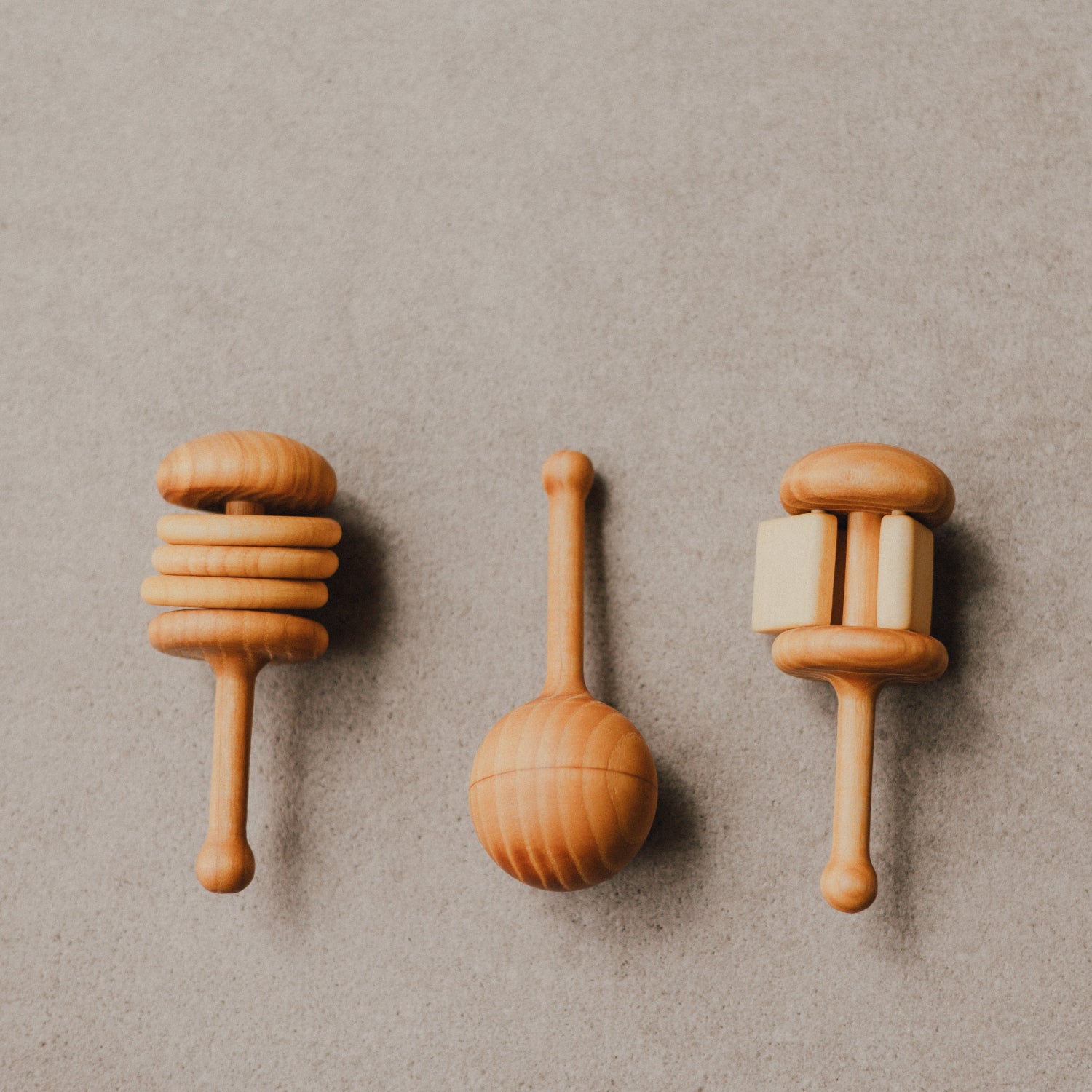 Three wooden baby rattles on a beige background