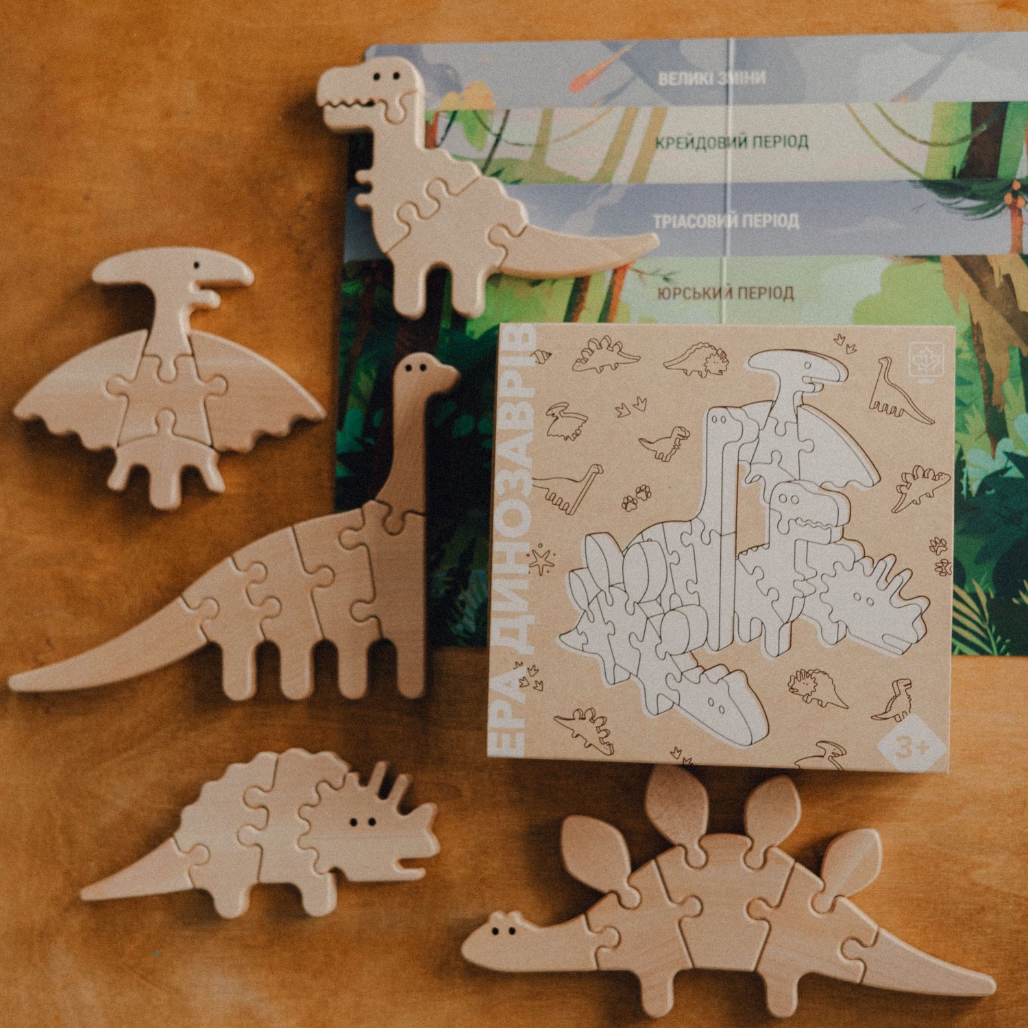 Wooden dinosaur puzzles on a wooden surface with packaging in the background