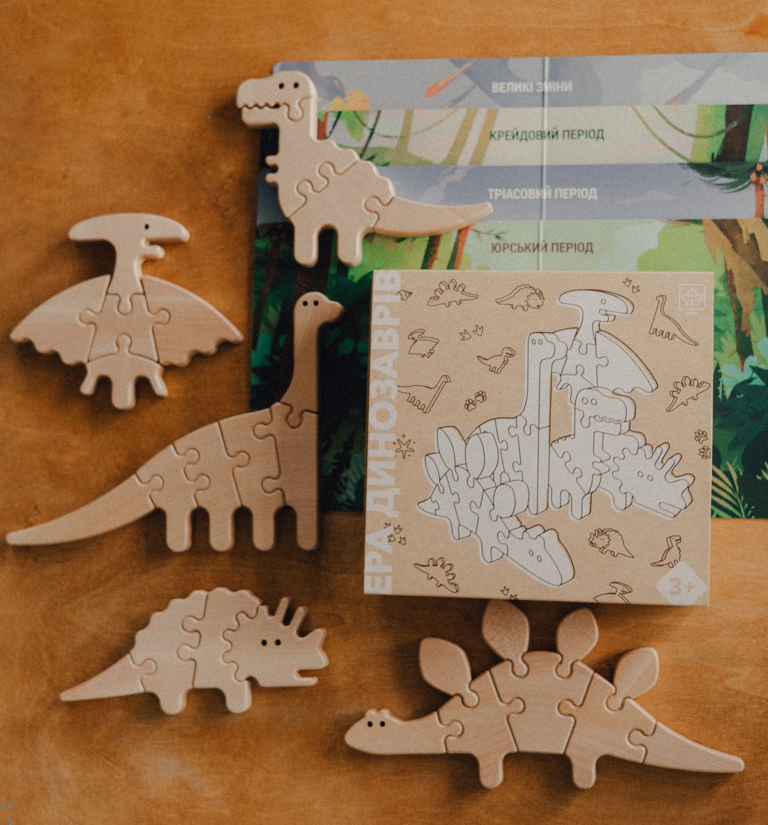 Wooden dinosaur puzzles on a wooden surface with packaging in the background