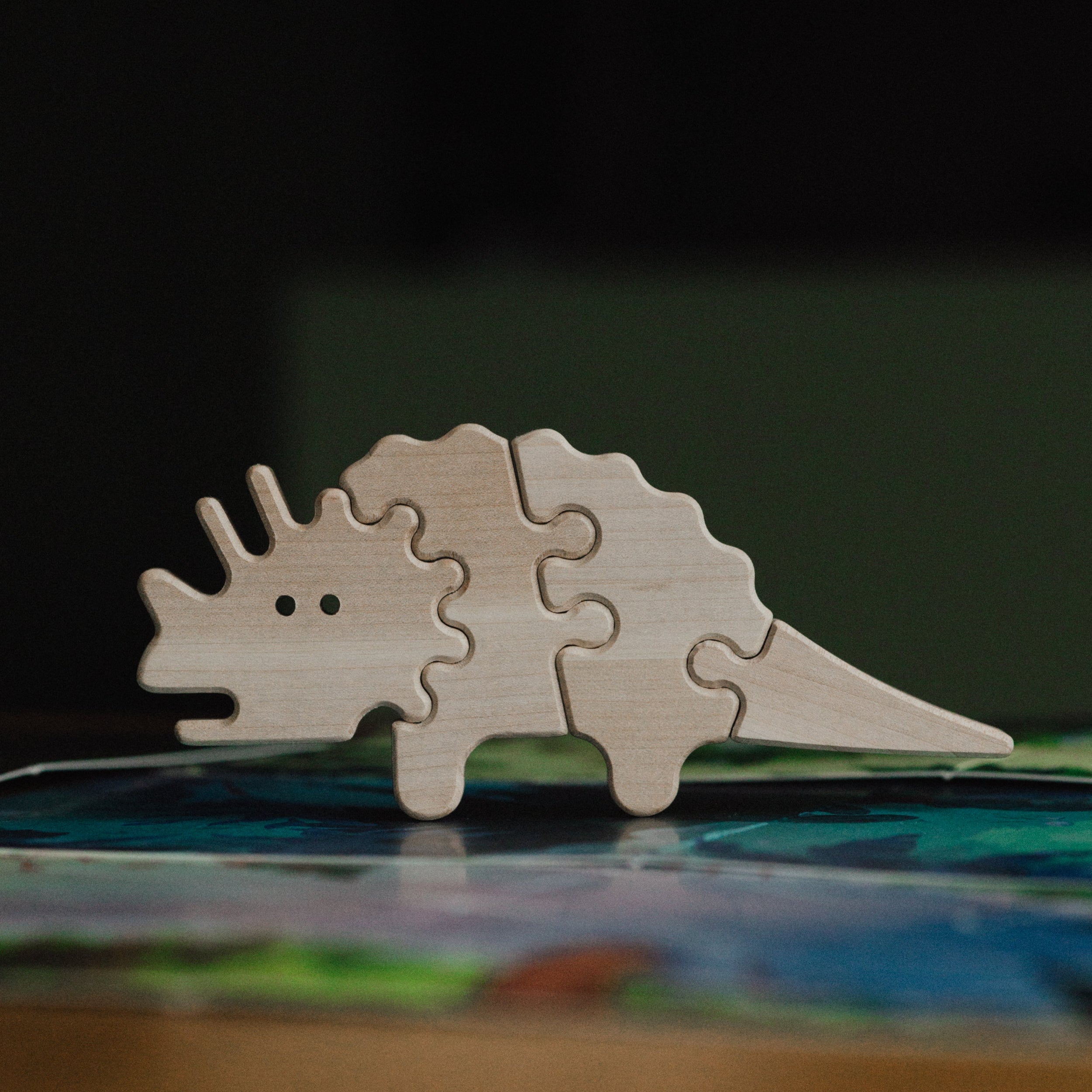 Wooden dinosaur puzzle on a book with a dark background