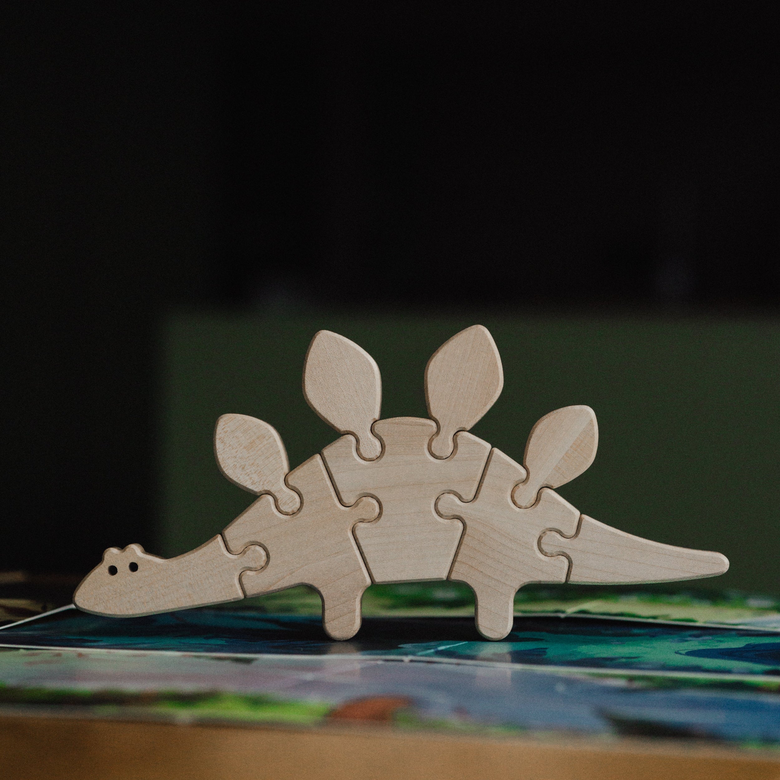 Wooden dinosaur puzzle on a table with a dark background