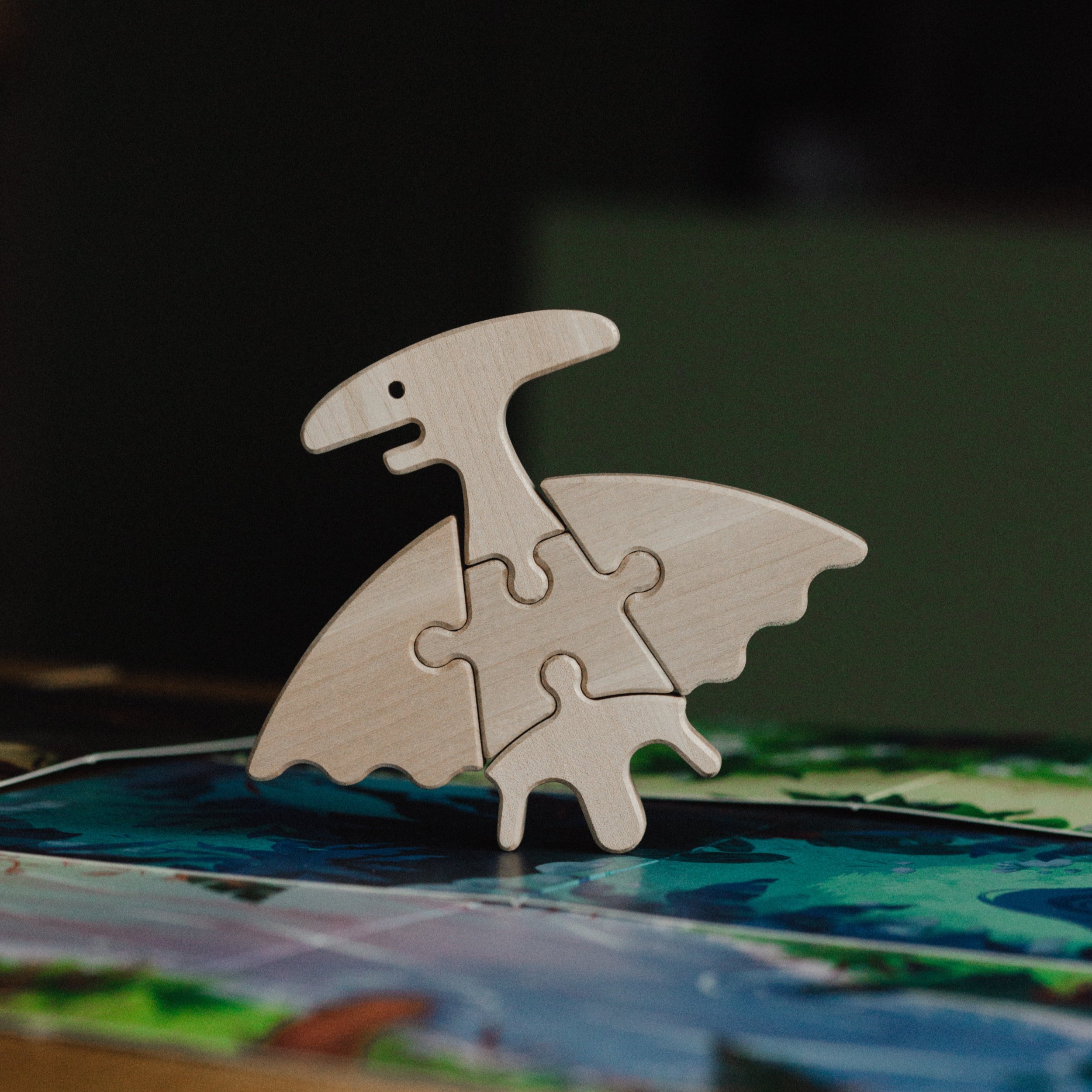 Wooden dinosaur puzzle piece on a colorful surface with a dark background