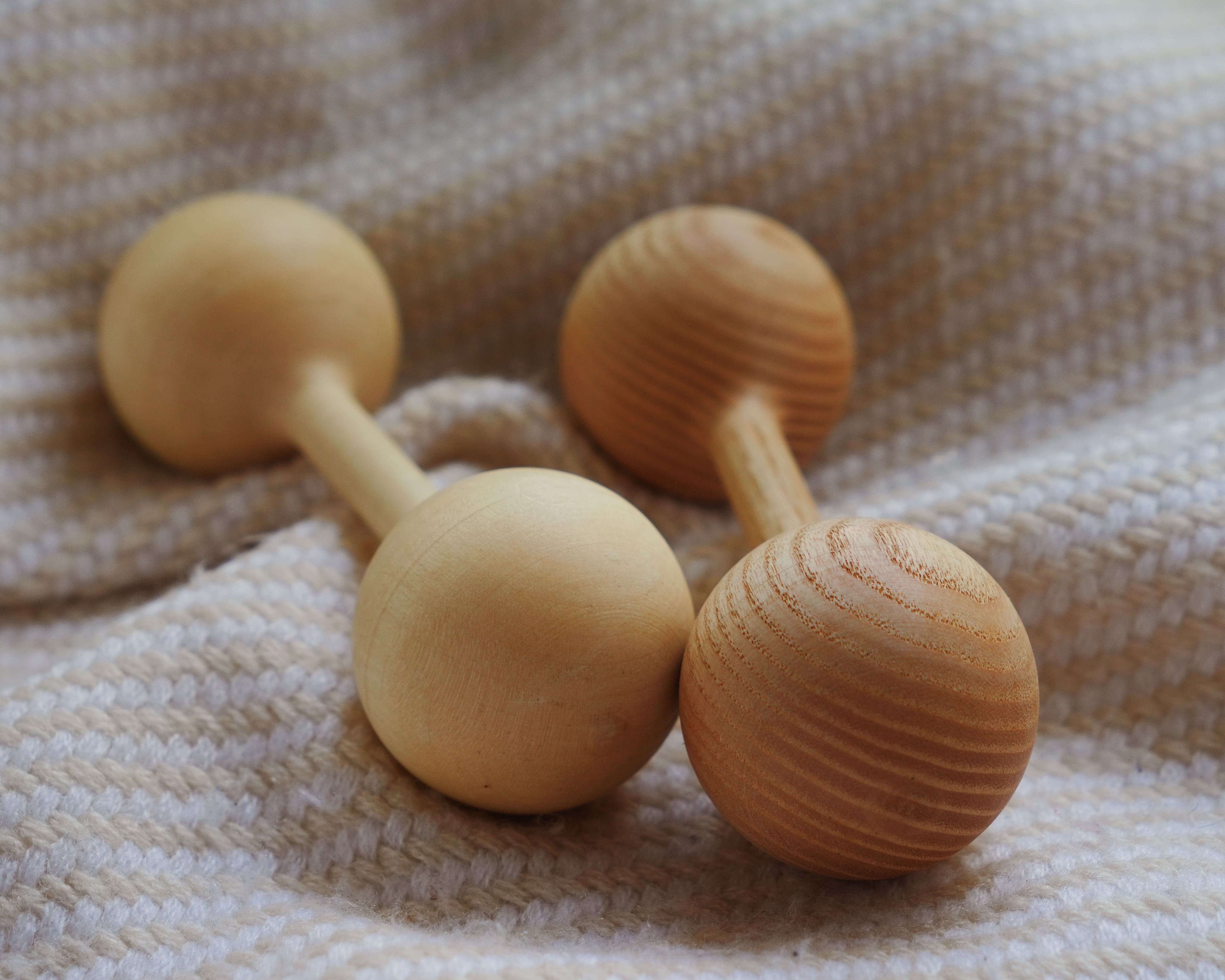 Two wooden dumbbells on a textured fabric background