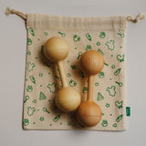 Wooden baby rattle on a fabric bag with green patterns