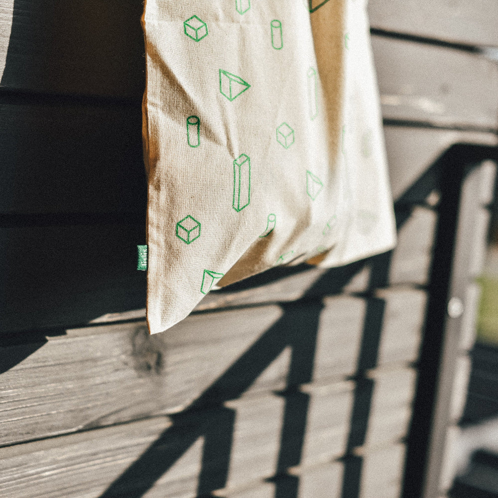 Beige bag with green geometric patterns hanging on a wooden deck