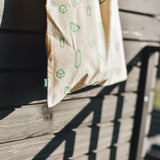 Beige bag with green geometric patterns hanging on a wooden deck